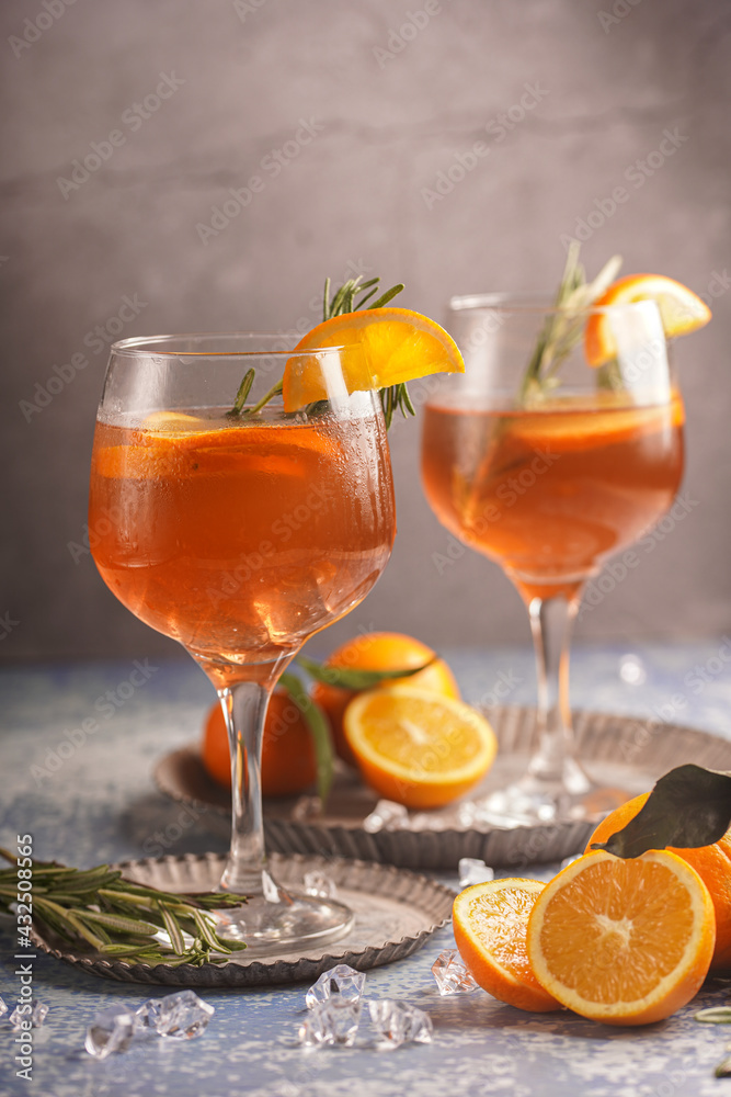 Orange christmas alcoholic beverage aperol spritz and lemonade with oranges, tangerines and rosemary in many glasses