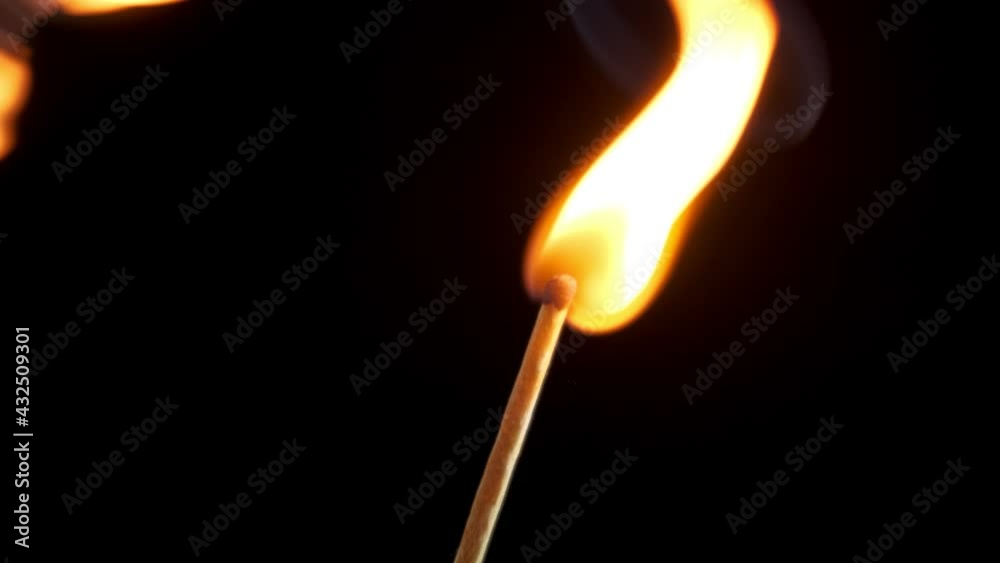 a burning match in hand, lights another on a black background a burning match in hand, lights another on a black background