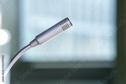 Seitliche Nahaufnahme eines Mikrofons in einem Konferenzraum mit einem großen Bildschirm im verschwommenen Hintergrund, isoliert, selektiver Fokus, viel Copy Space photo