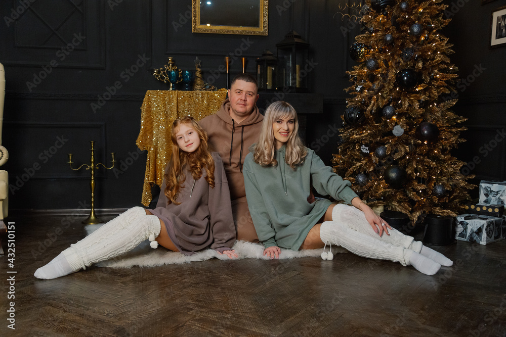 Happy family on the floor by the Christmas tree.