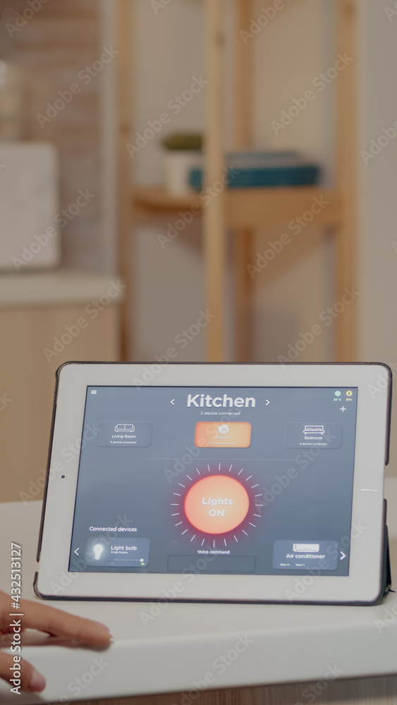 Young woman using smart home application with voice command to turn on the light by tablet. Lady using lighting control app in modern house with automation system controlling efficiency of energy