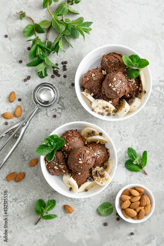 Chocolate and banana fruit ice cream with almond nuts served in bowls, top view