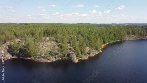 Aerial view of a cliff on lakeshore in Saimaa, Finland. Drone moving sideways. Beautiful summer day.  photo