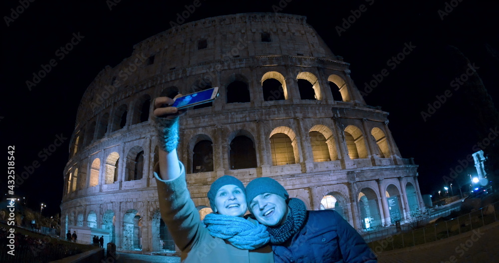 Selfie of tourists against Coliseum at night