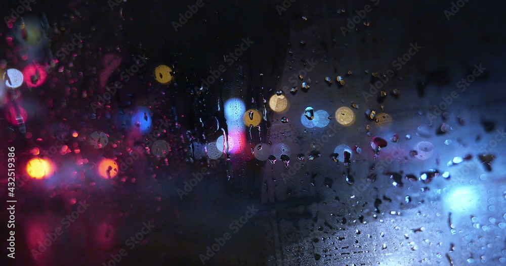 Fototapeta premium View of city through wet and weepeing car window