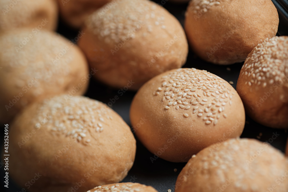 many baked sesame topping burger breads lay on oven tray waiting for cooking, shot with shallow focusing for using as background wallpaper. many baked sesame topping burger breads lay on oven tray waiting for cooking, shot with shallow focusing for using as background wallpaper.