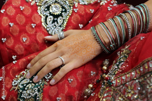 junge Hand mit schönem indischen Schmuck und vielen Amreifen auf rotem Tuch © Lisa