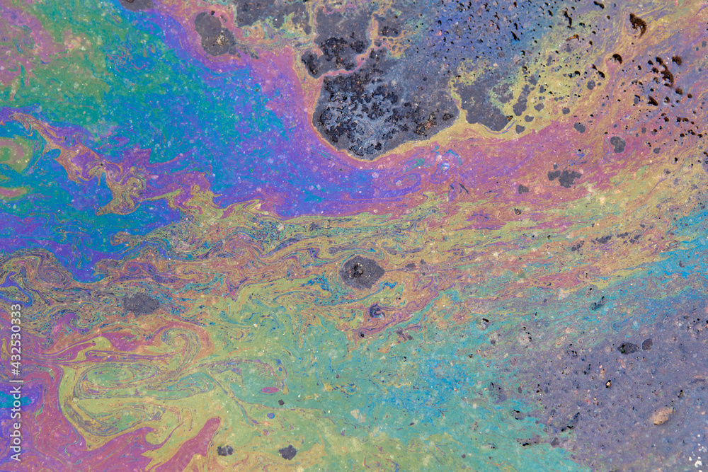 Colorful circular iridescent spot of gasoline or oil leakage on the asphalt.
