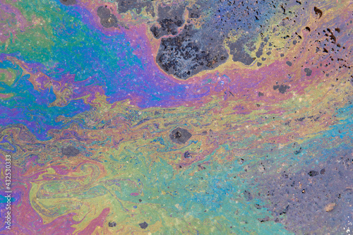 Colorful circular iridescent spot of gasoline or oil leakage on the asphalt.