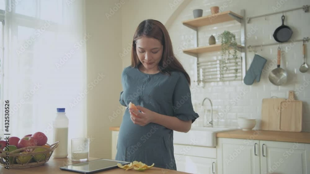 Pregnant woman concept of 4k Resolution. Asian girls eating oranges in the kitchen. Pregnant woman concept of 4k Resolution. Asian girls eating oranges in the kitchen.