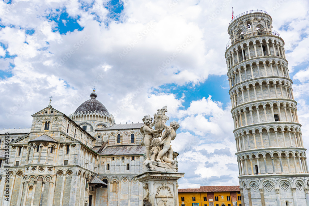 Fototapeta premium Fontana dei Putti, Tower and cathedral of the town of Pisa in Tuscany. On a cloudy day with blue sky.