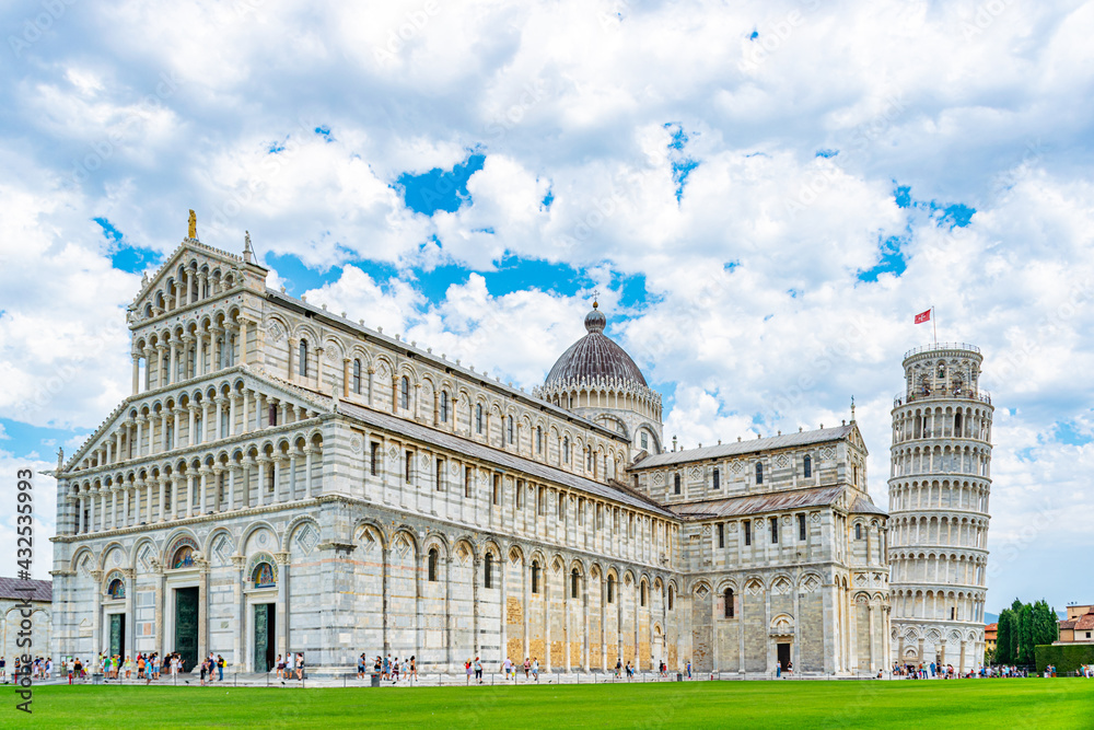 Cathedral of Pisa with its leaning tower on a beautiful day with clouds and blue sky in Tuscany,Italy.