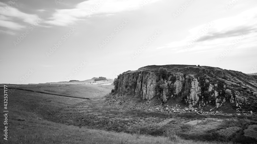 Northumberland UK: Hadrians Wall built on tall cliffs (Roman Wall) on a sunny summer day in the English countryside. In dramatic black and white