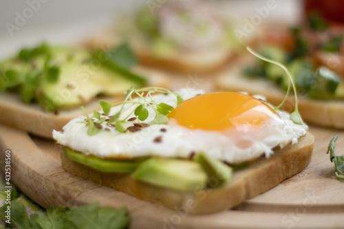 sandwich with avocado and fried egg, sprinkled with flax seeds and microgreens. Healthy sandwich with avocado