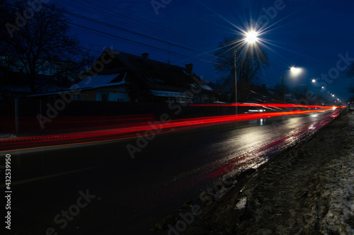 night warm photo of red light blur from car headlights, along the road with lantern light © VladR
