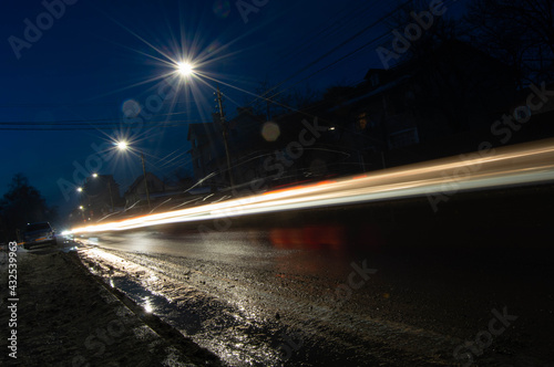 night photo of blurred warm light from car headlights along the road