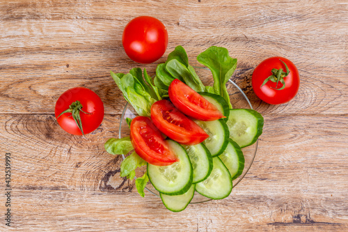 Vegetable slicing of cucumbers and tomatoes on a plate on a wooden background