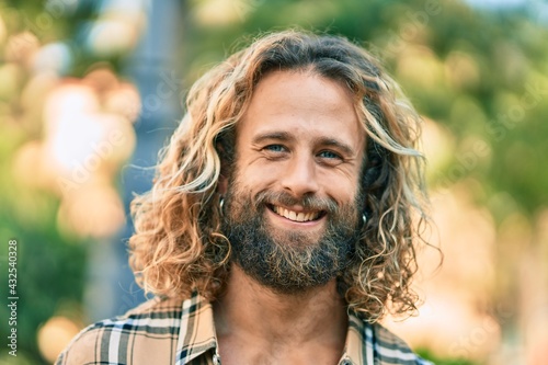 Young caucasian man with long hair smiling happy at the park.