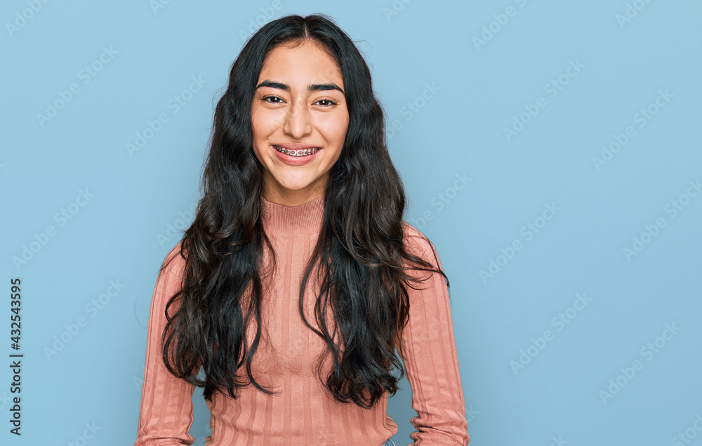 Fototapeta premium Hispanic teenager girl with dental braces wearing casual clothes with a happy and cool smile on face. lucky person.