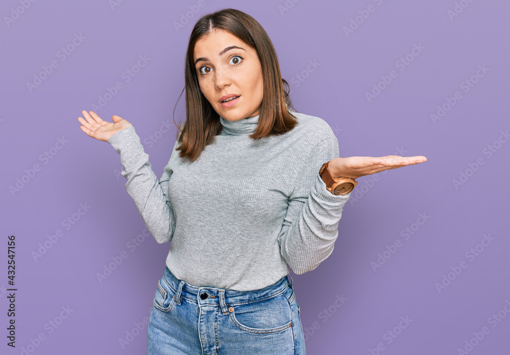 Young beautiful woman wearing casual turtleneck sweater clueless and confused expression with arms and hands raised. doubt concept. Young beautiful woman wearing casual turtleneck sweater clueless and confused expression with arms and hands raised. doubt concept.