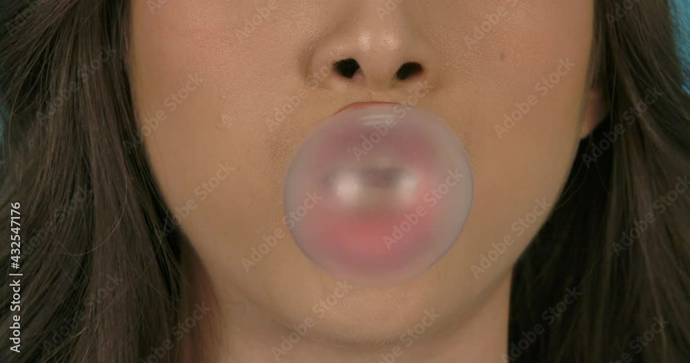 Portrait and big close up shot of young beautiful asian woman blowing gum in blue background. Fashion, travel and beauty concept.