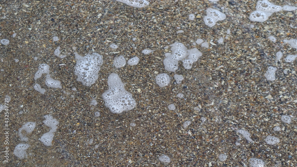 Unusual background of sand and small seashells filled with sea water with foam bubbles. Unusual background of sand and small seashells filled with sea water with foam bubbles.