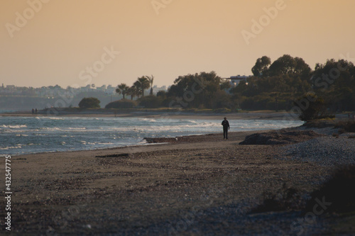 lonely man walking at sunset on the beach