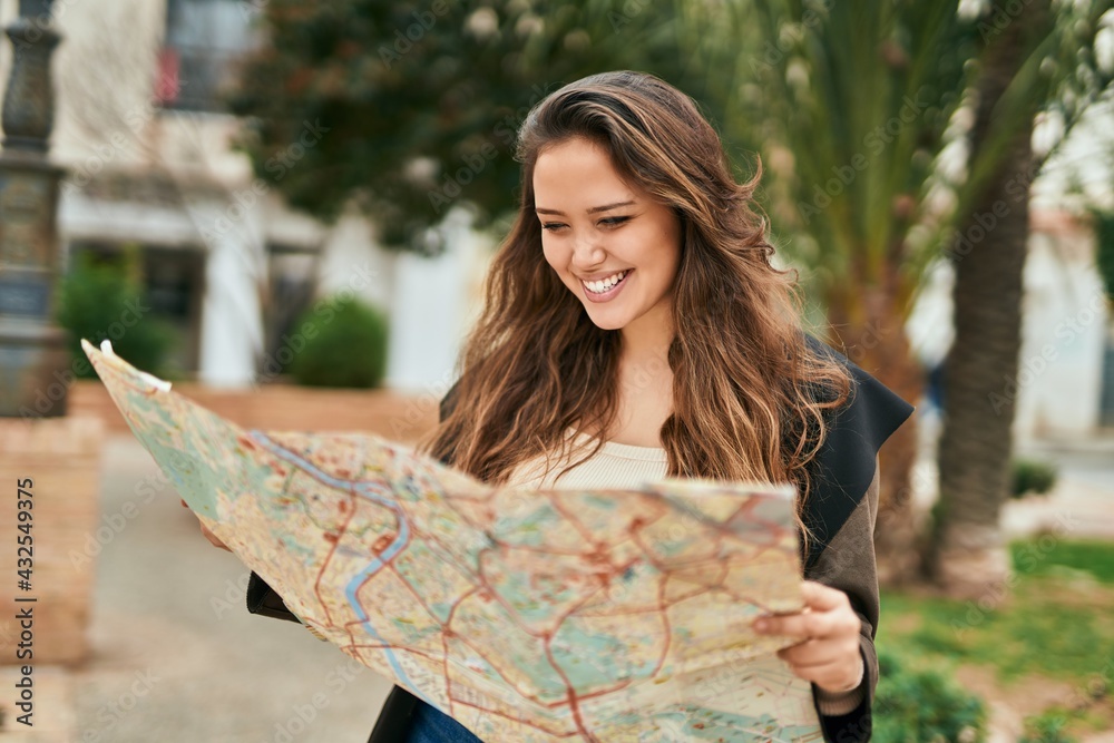 Naklejka premium Young hispanic tourist woman holding map at the city.