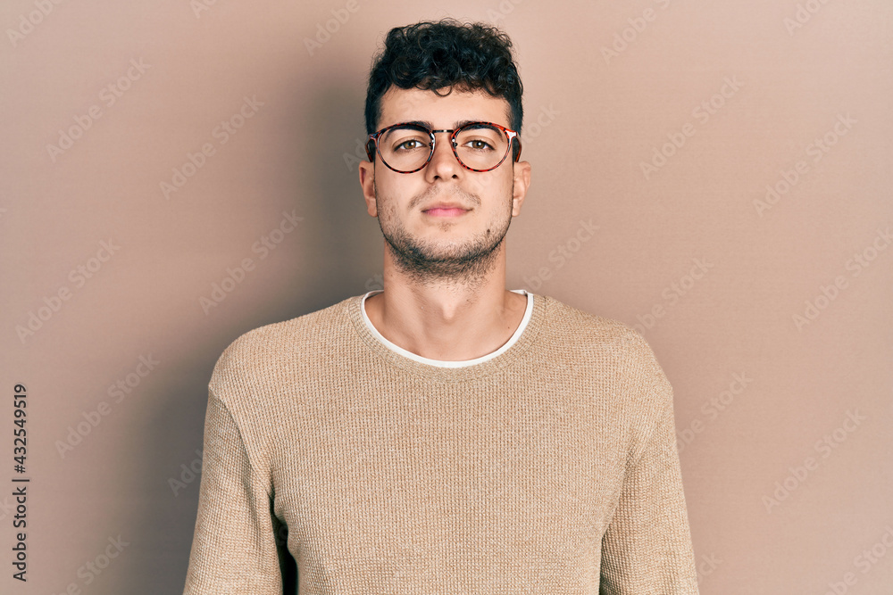 Young hispanic man wearing casual clothes and glasses relaxed with serious expression on face. simple and natural looking at the camera. Young hispanic man wearing casual clothes and glasses relaxed with serious expression on face. simple and natural looking at the camera.
