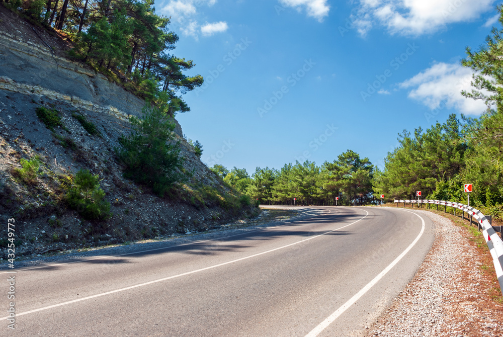 Mountain landscape. Mountain road, going away against the background of a blue sky and pines. Mountain landscape. Mountain road, going away against the background of a blue sky and pines.