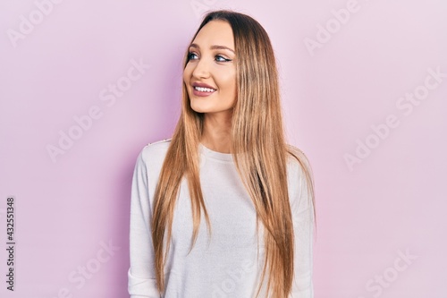 Young blonde girl wearing casual clothes looking to side, relax profile pose with natural face and confident smile.