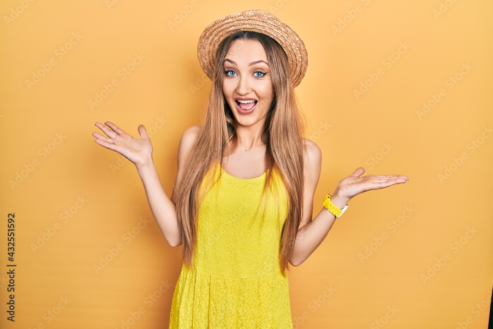 Young blonde girl wearing summer hat celebrating crazy and amazed for success with arms raised and open eyes screaming excited. winner concept Young blonde girl wearing summer hat celebrating crazy and amazed for success with arms raised and open eyes screaming excited. winner concept