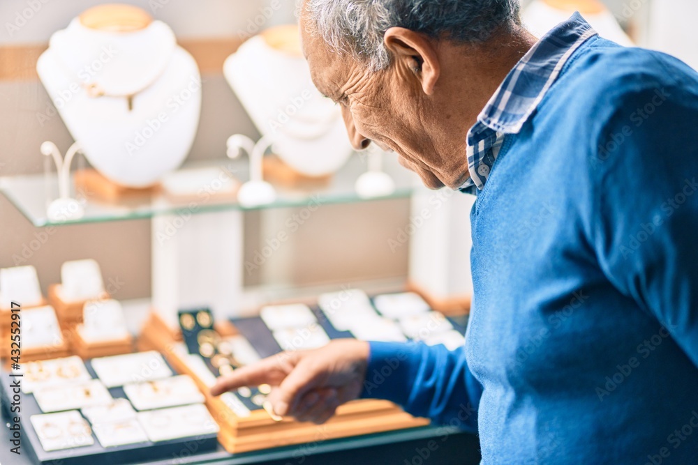 Senior grey-haired man smiling happy looking to showcase jewelry shop. Senior grey-haired man smiling happy looking to showcase jewelry shop.