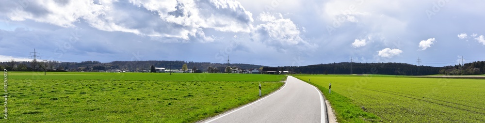 Rroad in the green nature with sky. Clouds rural landscape with fields in spring.