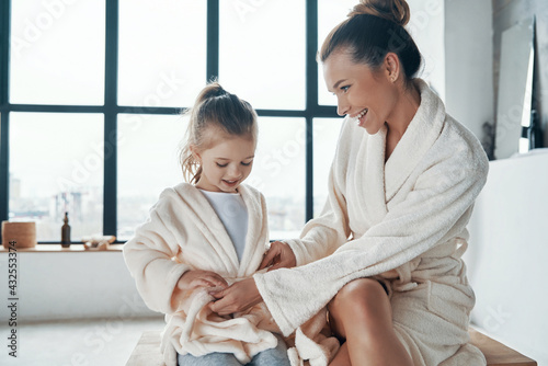 Mother with daughter in bathrobes smiling 
