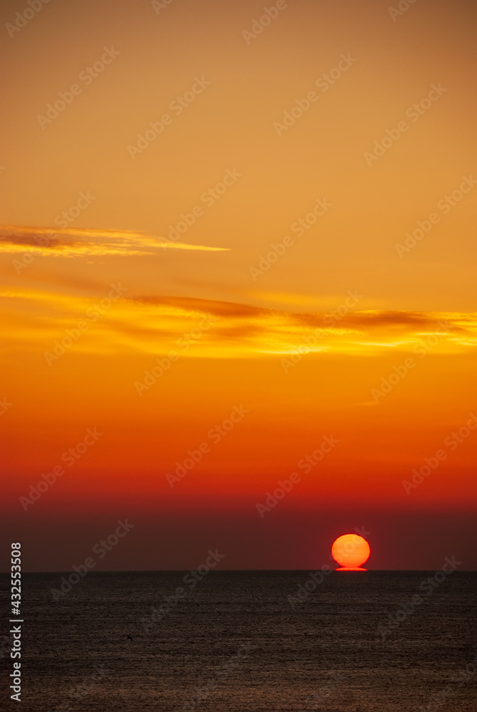 Seascape at sunset. The red disk of the sun is beyond the horizon.