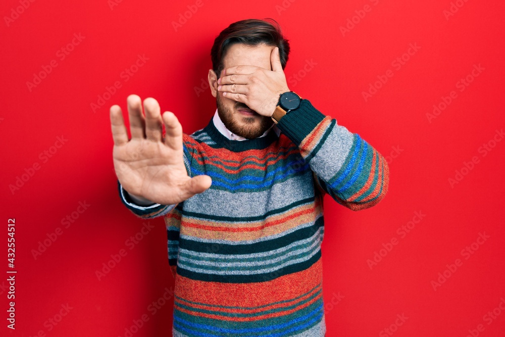 Handsome caucasian man with beard wearing elegant wool winter sweater covering eyes with hands and doing stop gesture with sad and fear expression. embarrassed and negative concept. Handsome caucasian man with beard wearing elegant wool winter sweater covering eyes with hands and doing stop gesture with sad and fear expression. embarrassed and negative concept.