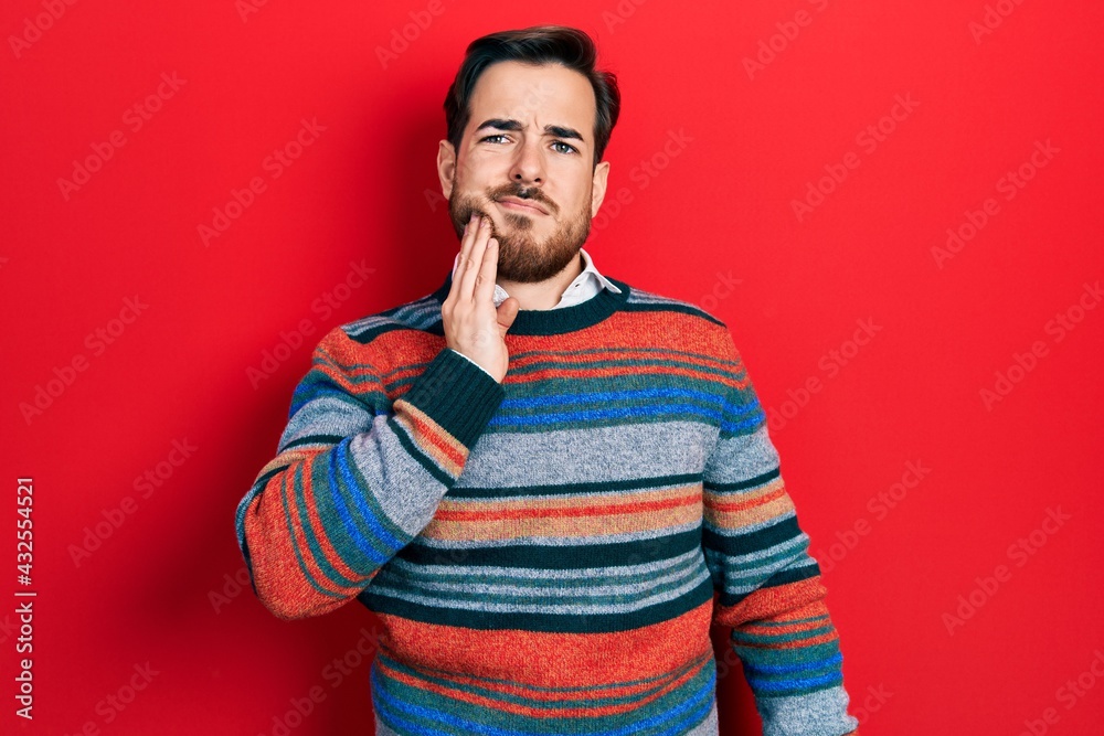 Handsome caucasian man with beard wearing elegant wool winter sweater touching mouth with hand with painful expression because of toothache or dental illness on teeth. dentist