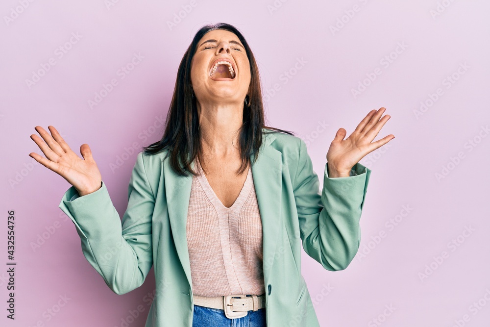 Middle age brunette woman wearing casual clothes celebrating mad and crazy for success with arms raised and closed eyes screaming excited. winner concept Middle age brunette woman wearing casual clothes celebrating mad and crazy for success with arms raised and closed eyes screaming excited. winner concept