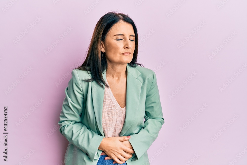 Middle age brunette woman wearing casual clothes with hand on stomach because indigestion, painful illness feeling unwell. ache concept. Middle age brunette woman wearing casual clothes with hand on stomach because indigestion, painful illness feeling unwell. ache concept.