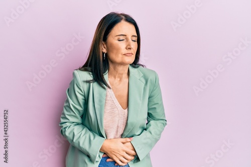 Middle age brunette woman wearing casual clothes with hand on stomach because indigestion, painful illness feeling unwell. ache concept.