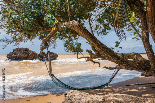 An abandoned hammock hung from a tree on an empty beach in Axim Ghana West Africa.