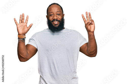 Young african american man wearing casual white tshirt showing and pointing up with fingers number eight while smiling confident and happy.
