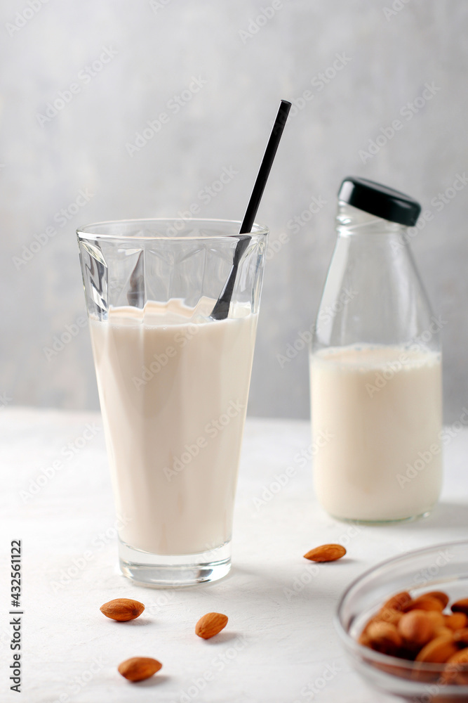 Almond milk gluten-free in glass containers on a light background. Organic natural vegetarian drink. Health concept. Vertical position Almond milk gluten-free in glass containers on a light background. Organic natural vegetarian drink. Health concept. Vertical position