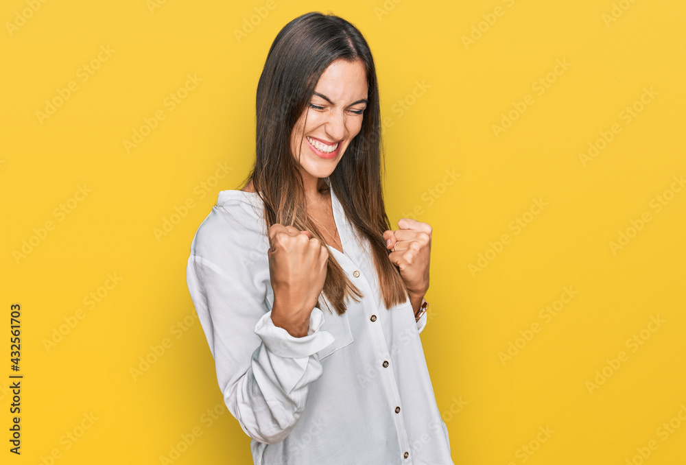 Young beautiful woman wearing casual clothes celebrating surprised and amazed for success with arms raised and eyes closed. winner concept. Young beautiful woman wearing casual clothes celebrating surprised and amazed for success with arms raised and eyes closed. winner concept.