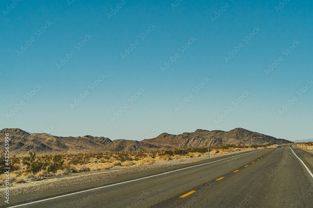Two lane road in the arid Sierra Nevada's leading to mountains against blue sky Two lane road in the arid Sierra Nevada's leading to mountains against blue sky