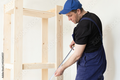 A professional carpenter makes a product from wooden boards and slats. Carpentry and manufacturing