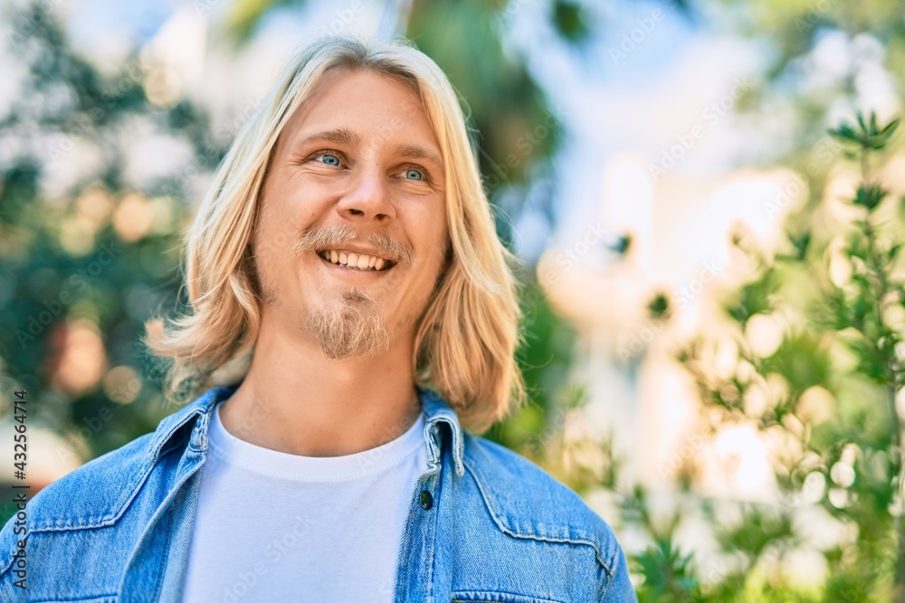 Young blond scandinavian man smiling happy standing at the park. Young blond scandinavian man smiling happy standing at the park.