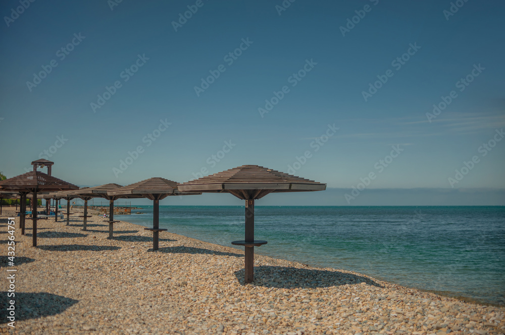 Wooden beach umbrellas by the sea in clear weather