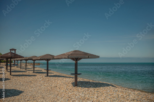 Fototapeta Naklejka Na Ścianę i Meble -  Wooden beach umbrellas by the sea in clear weather